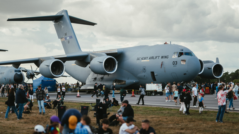 Stort militärt transportflygplan står uppställt med besökare samlade runt omkring.