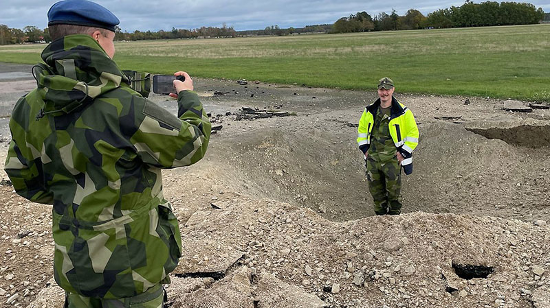 En militär som står i ett hål i marken blir fotad av en kollega