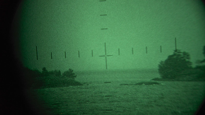 Mörkerkikarsikte över öppet vatten och skog