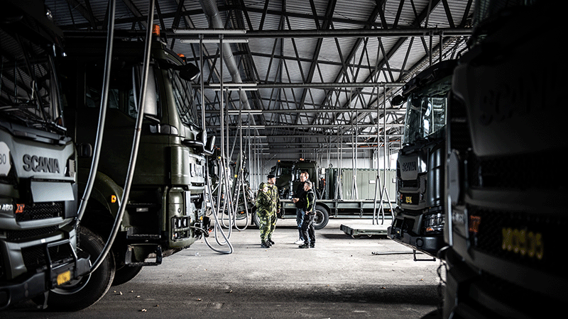 Militärer och civila pratar under ett skärmtak. 