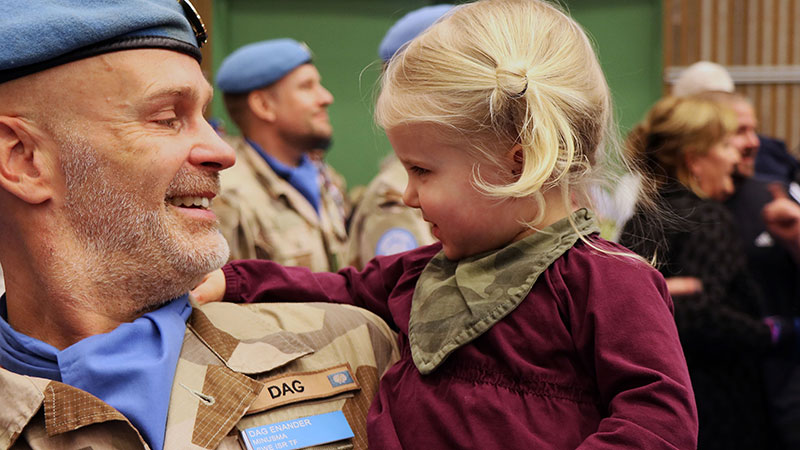 Dag Enander i militär uniform hållandes sin lilla dotter i famnen.