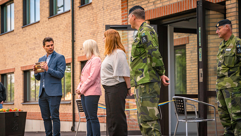 tre cviila personer och en militär står på rad.