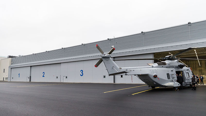 Helikopter med nosen inne i en hangar. 