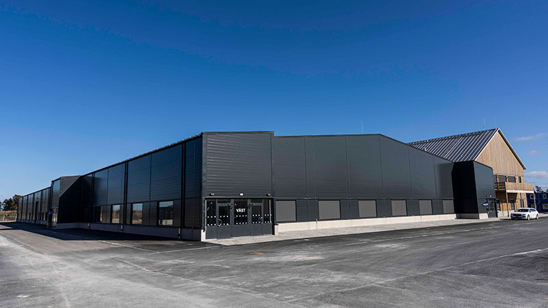 En stor svart byggnad med en del i trä