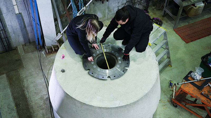 Två personer mäter diametern på en betongcirkel de sitter på. 