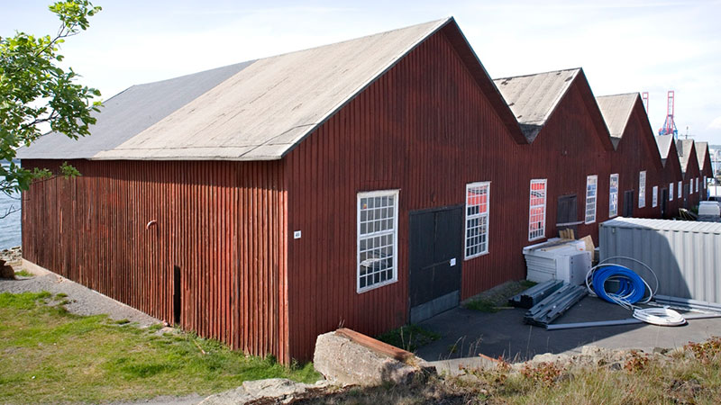 Rödmålad förrådsbyggnad med spetsiga tak i gammal stil. 