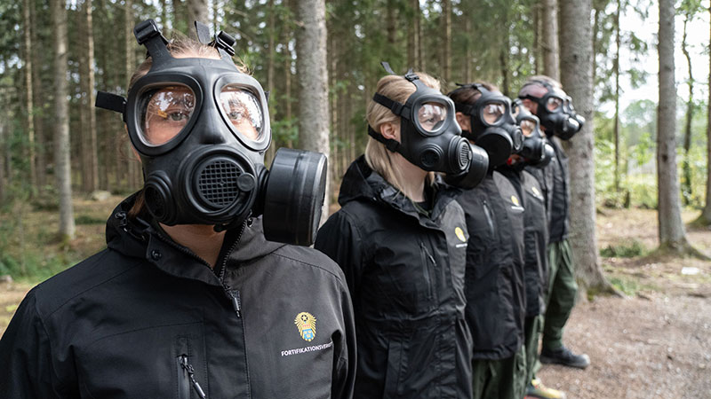 Medarbetare på rad iförda profilkläder och skyddmask