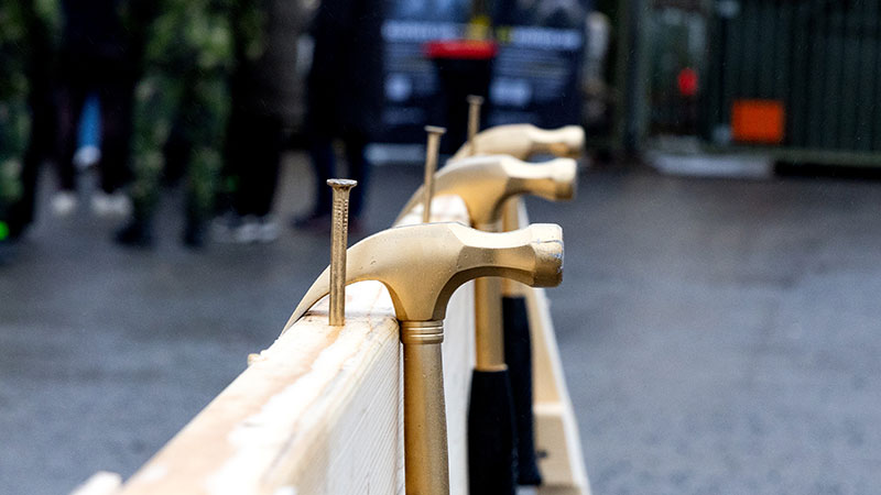 Tre hammare i guldfärg hänger på en planka