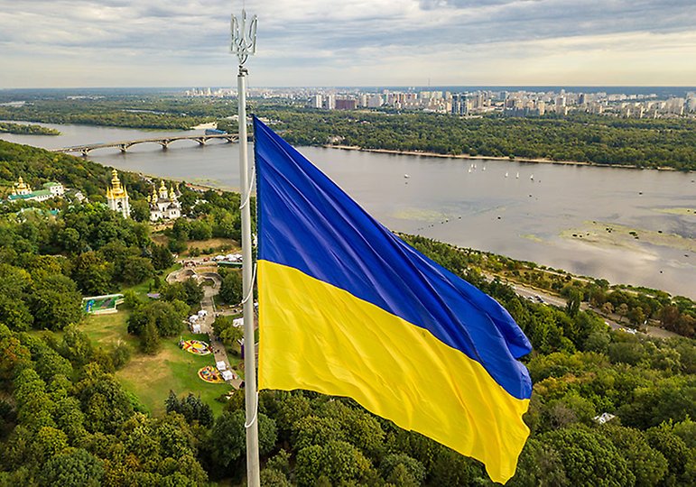 Utsikt över Kiev med en ukrainsk flagga i förgrunden.