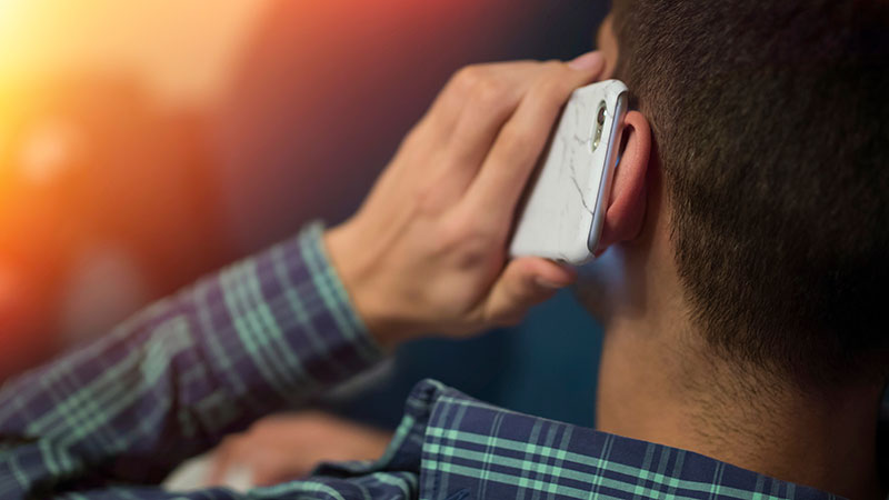 Man som håller mobiltelefon mot örat sedd bakifrån