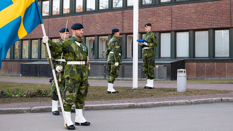 Försvarsmaktens högkvarter med soldater som håller svenska flagga